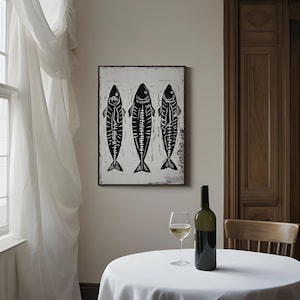 Op de afbeelding: Zwart-witte print van drie vissen die verticaal aan een witte achtergrond hangen. De vissen zijn gestileerd en hebben een eenvoudig ontwerp.