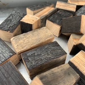 May include: A pile of small, rectangular wooden blocks. Some of the blocks are charred black, while others are a natural wood color.