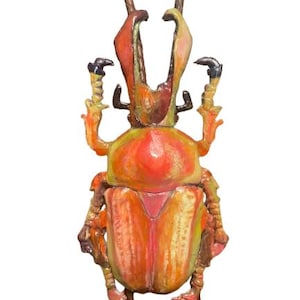 Puede incluir: Un bolo tie de escarabajo colorido, naranja, amarillo y rosa. El escarabajo está hecho de metal y tiene un diseño detallado. El bolo tie es una gran manera de agregar un toque de fantasía a cualquier atuendo.