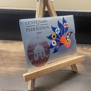 May include: A silver coin set commemorating the Centenary of Federation 2001. The packaging features a graphic of a map of Australia with colorful symbols and the text "Uncirculated Six Coin Set". The set is displayed on a small wooden easel.