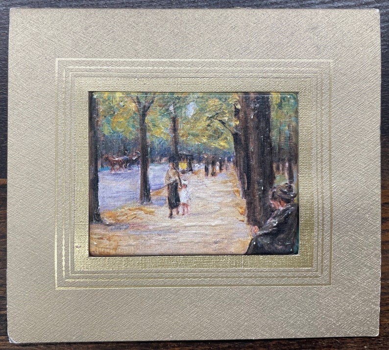 May include: An impressionistic painting of a tree-lined street scene, featuring figures strolling along a path. The artwork is framed in a gold-toned mat, enhancing the vintage aesthetic. The painting captures a moment in time with soft colors and brushstrokes.