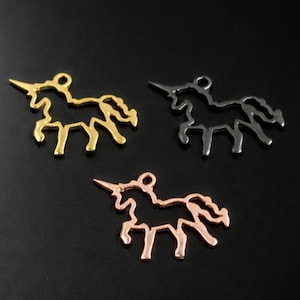 May include: Three metal unicorn charms in gold, silver, and rose gold. Each charm features a detailed outline of a unicorn with a horn and flowing mane. The charms are displayed against a black background.