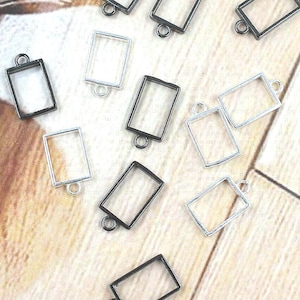 Hand holding 10x14mm brass open bezel rectangle frame pendant