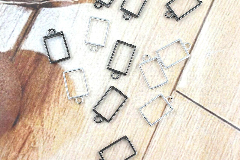 Hand holding 10x14mm brass open bezel rectangle frame pendant