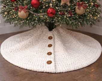 Könnte beinhalten: Ein geschmückter Weihnachtsbaum mit roten Kugeln, Schleifen aus Jute und sternförmigen Ornamenten mit der Aufschrift "Merry Christmas". Der Baum steht auf einem cremefarbenen Baumrock mit Knöpfen auf einem Holzboden.