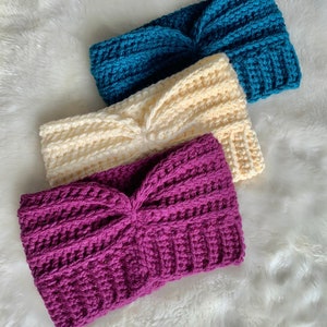 May include: Three crocheted headbands in different colors: teal, cream, and purple. The headbands are made with a thick yarn and have a knotted design.