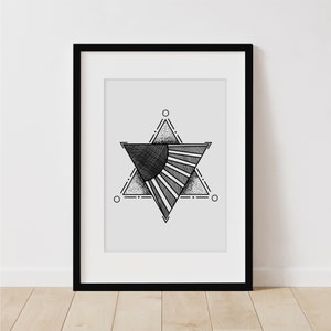 May include: Black and white geometric print of a star with a sunburst design inside. The print is framed in a black frame and is hanging on a white wall.