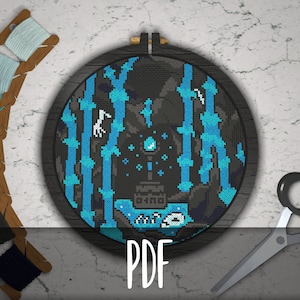 May include: A cross-stitch pattern in a wooden embroidery hoop. The pattern features a dark blue and black design with a white unicorn and a blue and white castle. The pattern is surrounded by a white background.