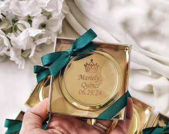 May include: Gold round favor boxes with green ribbon and a crown design. The box says "Mariely's Quince 06.29.24"