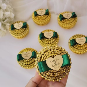 Può includere: Scatole regalo dorate con fiocchi verdi ed etichette a forma di cuore. Le etichette sono personalizzate con i nomi "Shakiba & Romish" e la data "11.11.22".