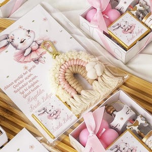 May include: A pink and white gift box with a white porcelain carousel, two pink candles, and a small card with a bunny illustration and the text "Feride Lidya".