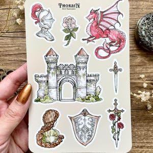May include: A sheet of stickers featuring a medieval castle, a knight's helmet, a red dragon, a sword, a shield, a rose, and a woman with long hair. The stickers are on a beige background with the text "THORAIN Art & Illustration".