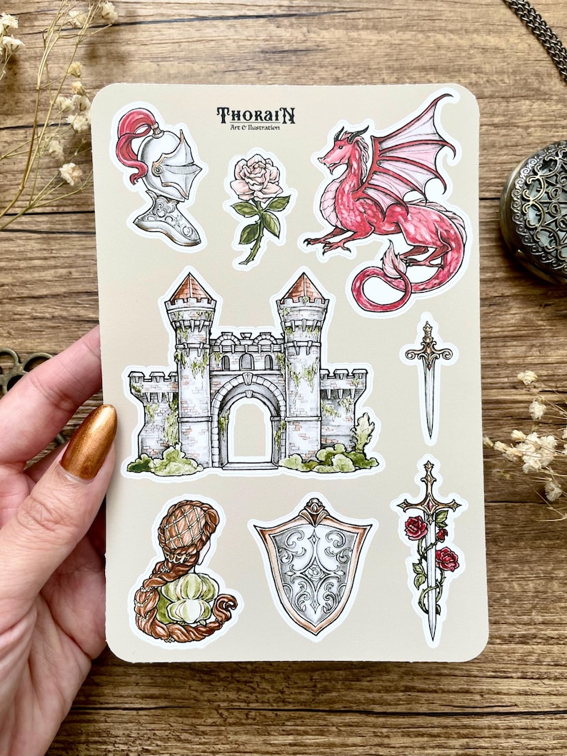 May include: A sheet of stickers featuring a medieval castle, a knight's helmet, a red dragon, a sword, a shield, a rose, and a woman with long hair. The stickers are on a beige background with the text "THORAIN Art & Illustration".