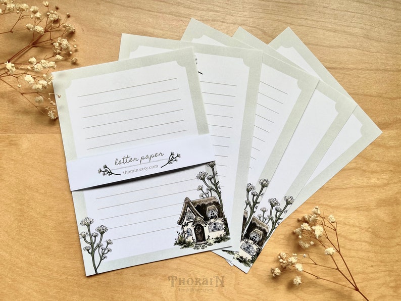 May include: A set of five blank letter writing sheets with a cottage and floral design. The paper is light green with white lines and a white border. The text "letter paper" and "thokai.etsy.com" is printed on the paper.