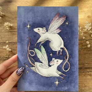 May include: A whimsical illustration of two white mice with fairy wings, set against a deep blue background with twinkling stars. The mice are depicted in mid-flight, with delicate wings in shades of pink and green. The artwork evokes a sense of fantasy and charm.