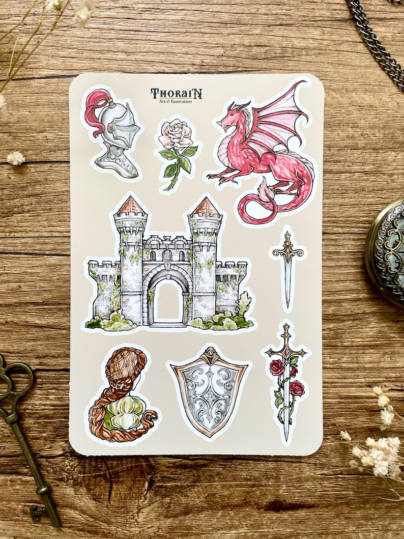 May include: A sheet of stickers featuring a castle, a dragon, a knight's helmet, a sword, a shield, and roses. The stickers are on a beige background with the text "THORAIN Art & Illustration".