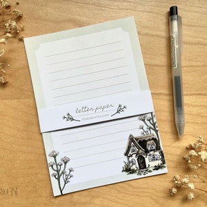 May include: A set of lined letter paper with a cottage illustration and floral accents. The paper has a light green background and the text "letter paper thorain.etsy.com" is printed on the bottom.