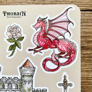 May include: A set of stickers featuring a red dragon with pink wings, a stone castle with a green ivy, a white rose with green leaves, and a silver sword with a gold handle. The stickers are on a beige background with the text "THORAIN Art & Illustration".