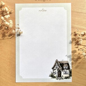May include: A printable stationery design featuring a cottage with a thatched roof and a green ivy vine. The design includes the word "notes" at the top of the page.