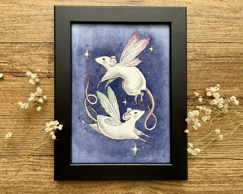 May include: A framed art print featuring two white mice with fairy wings, set against a dark blue background with stars. The mice are depicted in flight, with one having pink wings and the other green. The frame is black.