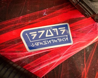 Op de afbeelding: Een blauwe en zilveren sticker met de tekst "ラファエル" en "リファレンス" in een futuristisch lettertype.