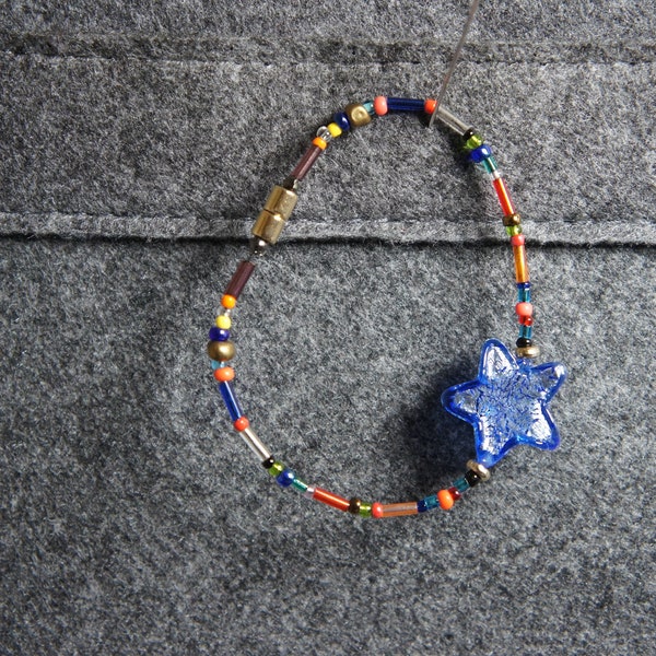 Bracelet avec perle de Murano étoile bleue givrée et petites perles montées sur cable acier, fermoir magnétique cylindrique doré