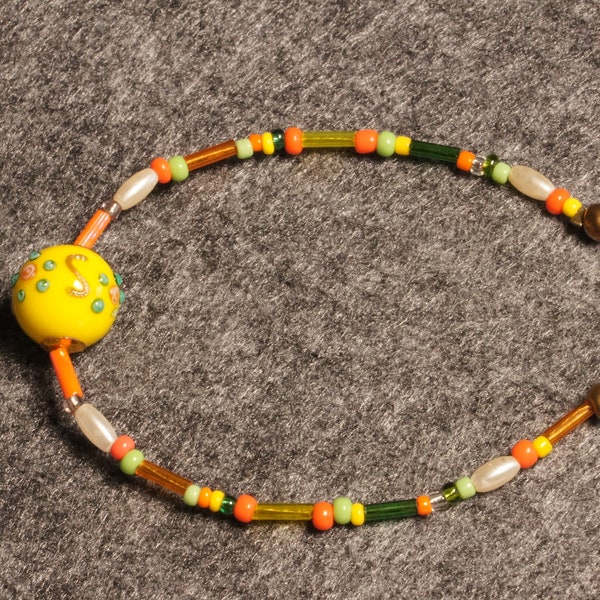 Bracelet Murano avec perle jaune citron montée sur câble acier gainé et perles assorties. Fermoir en métal  mousqueton coloris bronze
