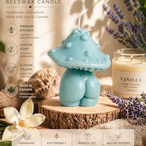 Op de afbeelding: Een lichtblauwe, gebogen bijenwaskaars in de vorm van een paddenstoel met een witte lont, op een houten schijf. De kaars is handgemaakt in Canada en heeft de tekst "CURVY MUSHROOM BEESWAX CANDLE". Een vanille geurkaars en lavendel takjes zijn op de achtergrond.
