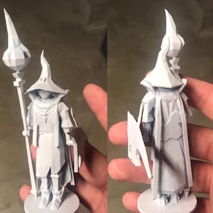 Könnte beinhalten: Eine weiße 3D-gedruckte Figur eines Zauberers mit einem spitzen Hut und einem Stab. Der Zauberer steht auf einem runden Sockel.