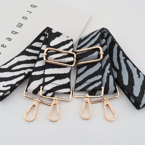 May include: Two adjustable straps with gold-tone hardware. One strap is black and white zebra print, the other is black and grey zebra print.