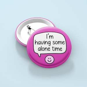 May include: Pink button badge with a speech bubble that says "I'm having some alone time" and a smiley face.