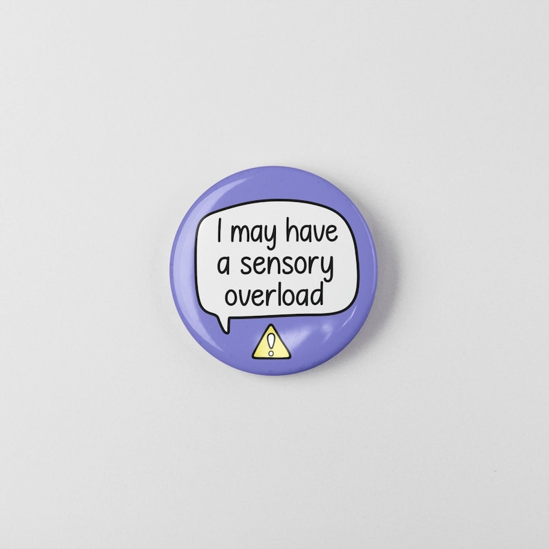 May include: Purple button with a white speech bubble that says "I may have a sensory overload" with a yellow exclamation point in a triangle.