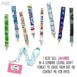 Op de afbeelding: Een verzameling kleurrijke lanyards met verschillende ontwerpen, waaronder madeliefjes, katten en inspirerende zinnen als "Just Be Kind" en "I Have a Hidden Disability". Elke lanyard heeft een metalen sluiting. Een roze label leest "I am Tired".