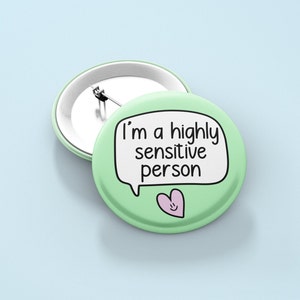 May include: A green button with a white speech bubble that says "I'm a highly sensitive person". A pink heart with a smiley face is below the speech bubble.