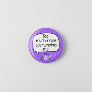 May include: Purple button with a speech bubble that says "Too much noise overwhelms me" and a black and white illustration of headphones.