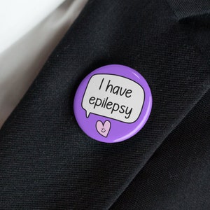May include: Purple button with a speech bubble that says "I have epilepsy" and a pink heart with a smiley face.