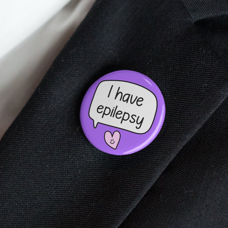 May include: Purple button with a speech bubble that says "I have epilepsy" and a pink heart with a smiley face.