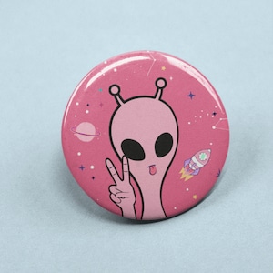 May include: Pink alien with a peace sign and a tongue sticking out on a pink background with stars and a rocket ship.