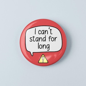 Op de afbeelding: Een ronde rode pin-back button met een witte tekstballon met de zwarte tekst "I can't stand for long" en een geel driehoekig waarschuwingsicoon met een uitroepteken onderaan op de voorzijde van de button.