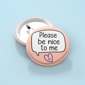 Peut inclure: Un bouton rose avec une bulle de dialogue blanche qui dit "S'il vous plaît, soyez gentil avec moi" et un cœur rose avec un visage souriant.