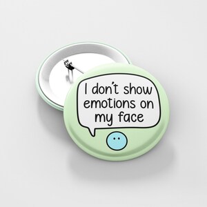 May include: A green button with a white speech bubble that says "I don't show emotions on my face". A blue smiley face is below the speech bubble.