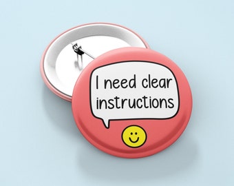 May include: A pink button with a white speech bubble that says "I need clear instructions" and a yellow smiley face.
