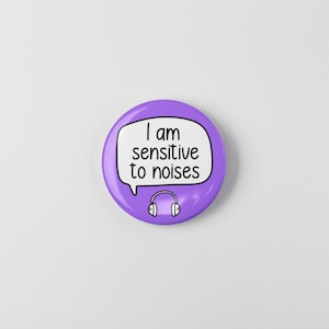 May include: Purple button with a white speech bubble that says "I am sensitive to noises" and a white headphone icon.