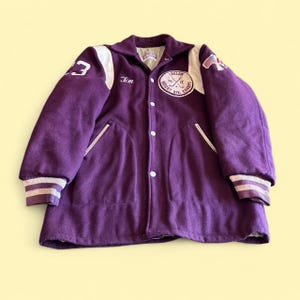 May include: A purple varsity jacket with white sleeves, featuring the name Tim embroidered on the chest, a circular patch reading Ludlow Weight Div. Champs 76 77, a number 23 on the shoulder, and a small American flag patch on the upper sleeve.
