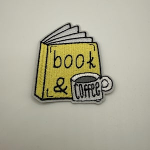 Può includere: Toppa ricamata raffigurante un libro giallo con la scritta "book" e una tazza di caffè con la scritta "coffee". La toppa ha un bordo bianco su sfondo bianco. Il libro è aperto, con pagine bianche.