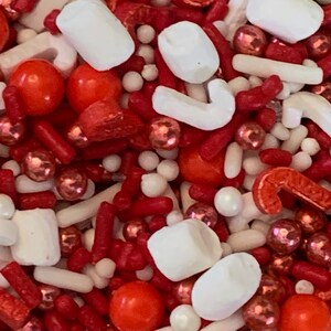 May include: A festive mix of red, white, and pink sprinkles. The assortment includes candy canes, round spheres, rod-shaped sprinkles, and marshmallow shapes. This mix is perfect for decorating baked goods for the holidays.