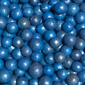 May include: Close-up of a pile of blue, spherical candies. The candies have a glossy finish and vary slightly in shade, ranging from bright to deep blue. The image is a full frame, showing the candies filling the entire space.