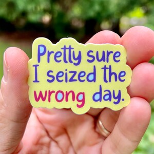May include: Yellow sticker with the text "Pretty sure I seized the wrong day." in purple and pink lettering.