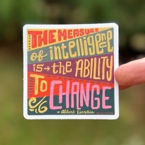 May include: A colorful sticker with the quote "The measure of intelligence is the ability to change" by Albert Einstein. The quote is written in a hand-drawn style with a mix of red, yellow, pink, and blue colors.