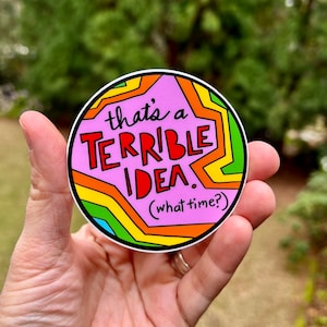 May include: A pink circle sticker with a rainbow border. The sticker says "that's a TERRIBLE IDEA. (what time?)"